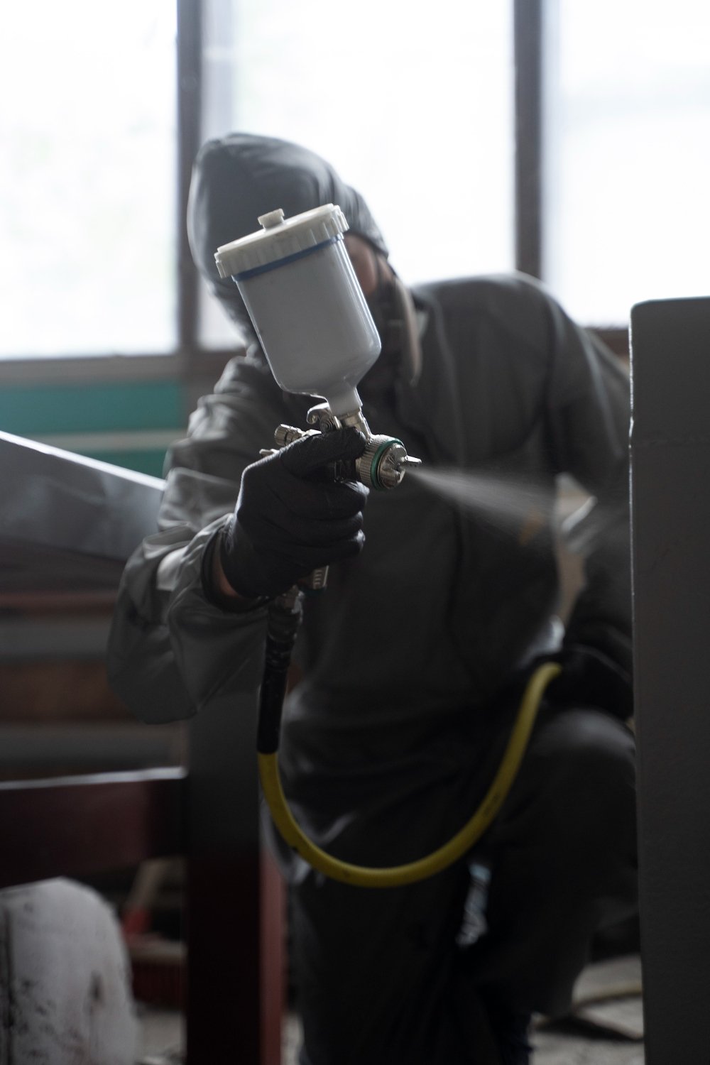 Pracownik maluje powierzchnię za pomocą ręcznego pistoletu natryskowego Krautzberger